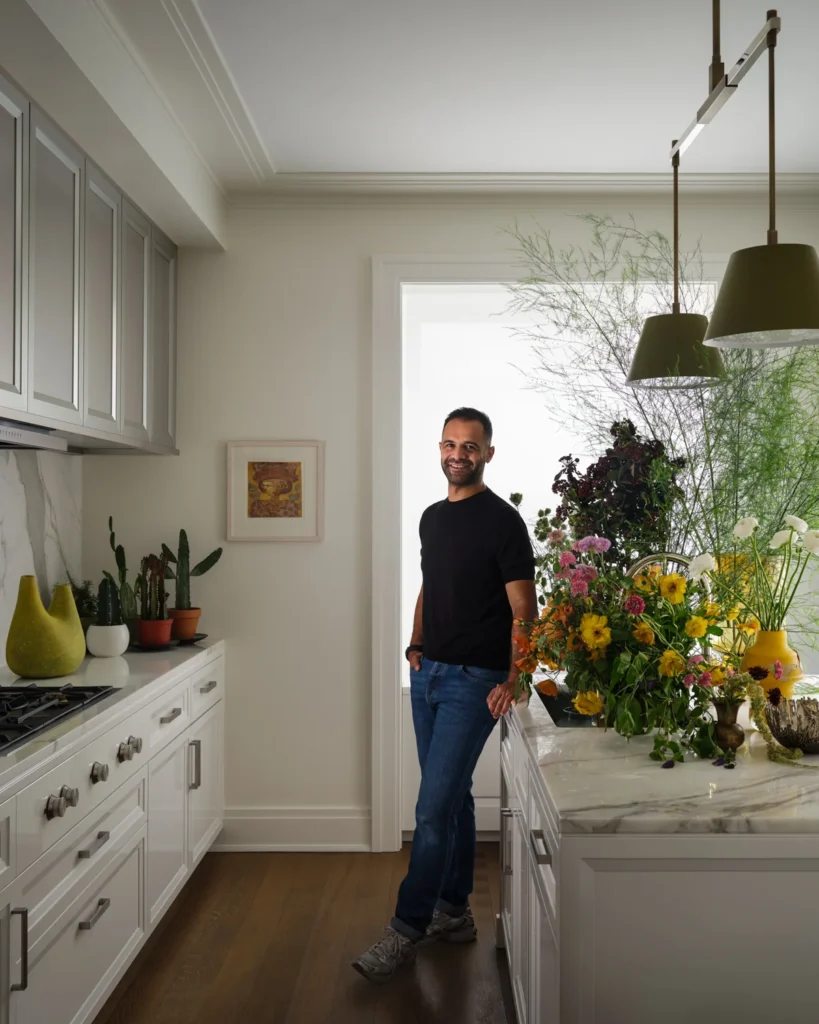 Ahmad AbouZanat standing beside a kitchen island filled with colorful flowers, with potted cacti along the counter.